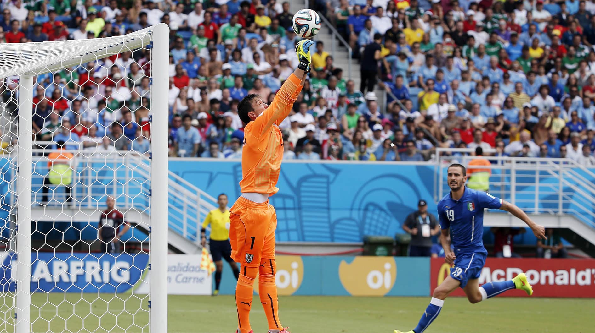 Uruguay goalkeeper Fernando Muslera (1) punches the ball clear of Italy defender Leonardo Bonucci (19) during the first half of a 2014 World Cup game at Estadio das Dunas.