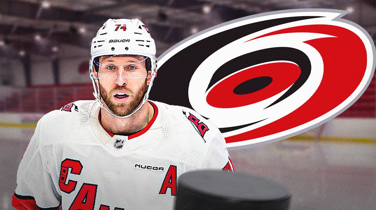 Jaccob Slavin in middle of image looking hopeful, Carolina Hurricanes logo, hockey rink in background