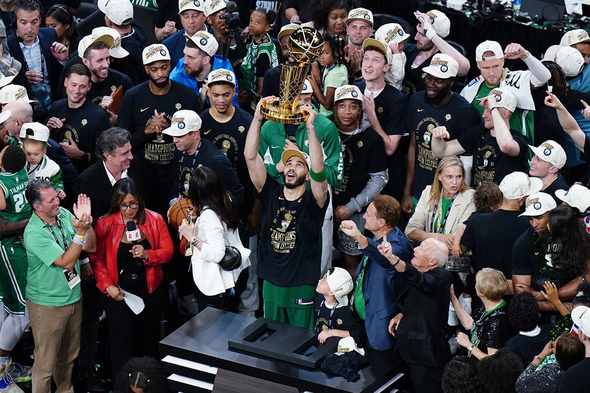 Boston Celtics forward Jayson Tatum (0) celebrates with the trophy on the podium after defeating the Dallas Mavericks in the 2024 NBA Finals at TD Garden. 
