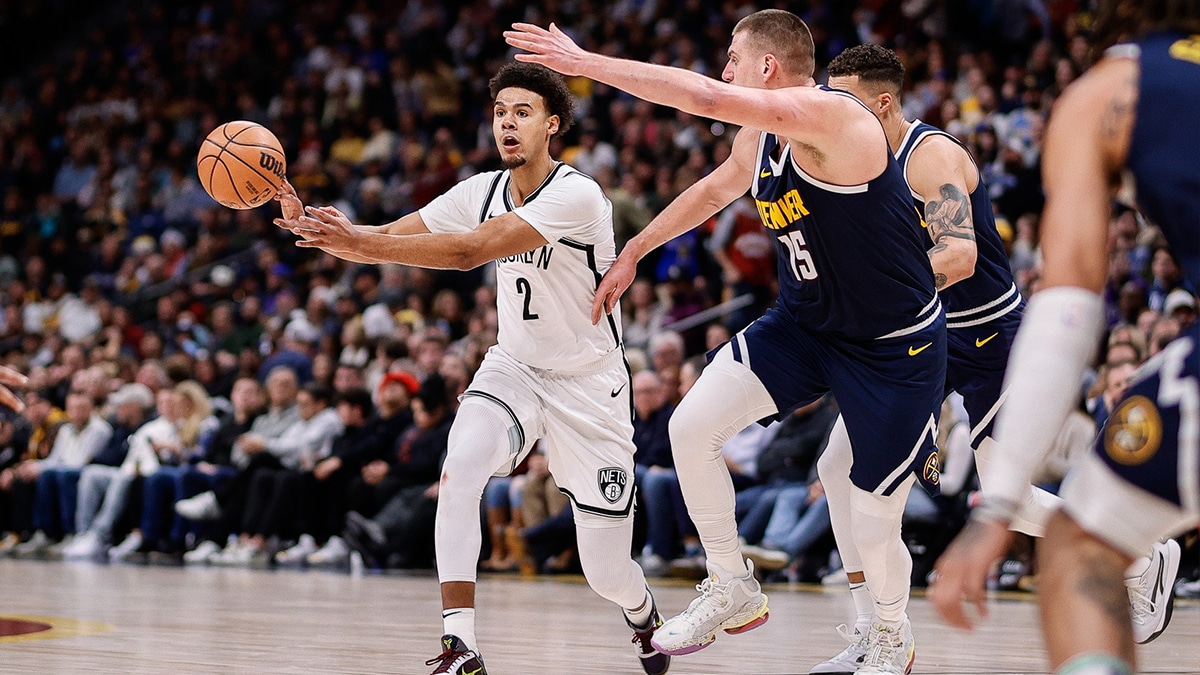 Brooklyn Nets forward Cam Johnson (2) passes the ball as Denver Nuggets center Nikola Jokic (15) guards in the second quarter at Ball Arena.