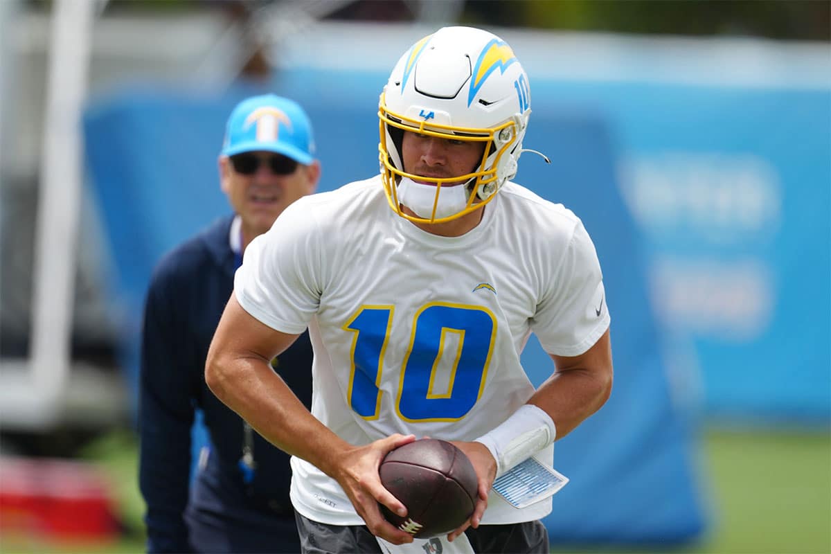 Los Angeles Chargers quarterback Justin Herbert (10) hands the ball off as coach Jim Harbaugh watches during organized team activities at the Hoag Performance Center.