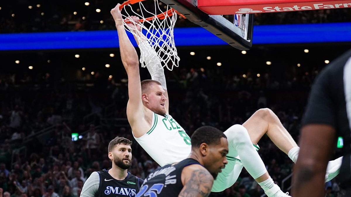 Boston Celtics center Kristaps Porzingis (8) dunks against Dallas Mavericks forward P.J. Washington (25) and forward Maxi Kleber (42) in the third quarter during game one of the 2024 NBA Finals at TD Garden