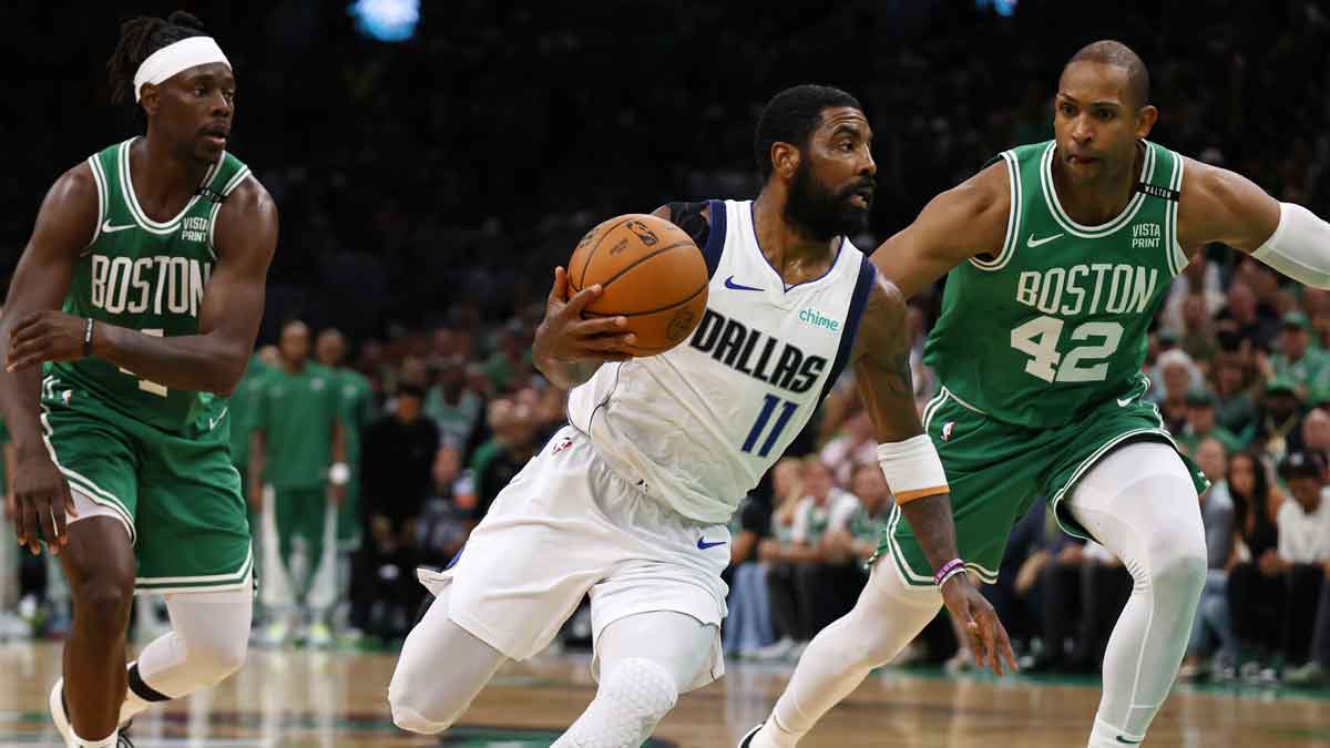 Dallas Mavericks guard Kyrie Irving (11) drives to the basket against Boston Celtics guard Jrue Holiday (left) and center Al Horford (right) during the second quarter in game five of the 2024 NBA Finals at TD Garden.