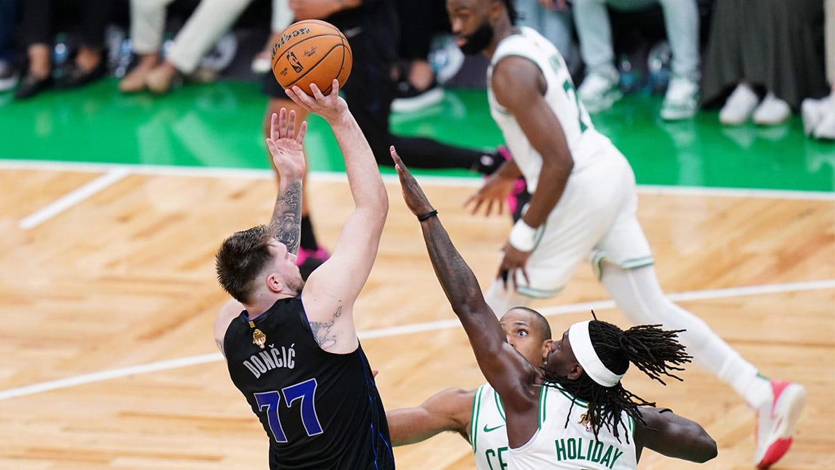 Dallas Mavericks guard Luka Doncic (77) shoots against Boston Celtics center Al Horford (42) and guard Jrue Holiday (4) in the fourth quarter during game one of the 2024 NBA Finals at TD Garden.