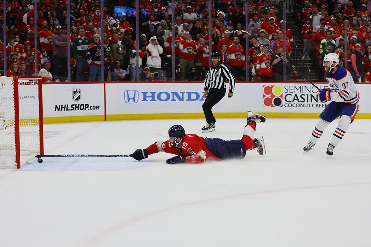 Florida Panthers forward Matthew Tkachuk (19) reaches for the puck on an empty net attempt on goal by Edmonton Oilers forward Connor McDavid (97) during the third period in game five of the 2024 Stanley Cup Final at Amerant Bank Arena
