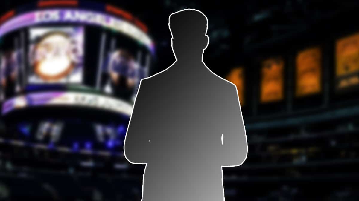 Image: silhouette of a person in a suit in the sidelines coaching, Los Angeles Lakers logo in the background.