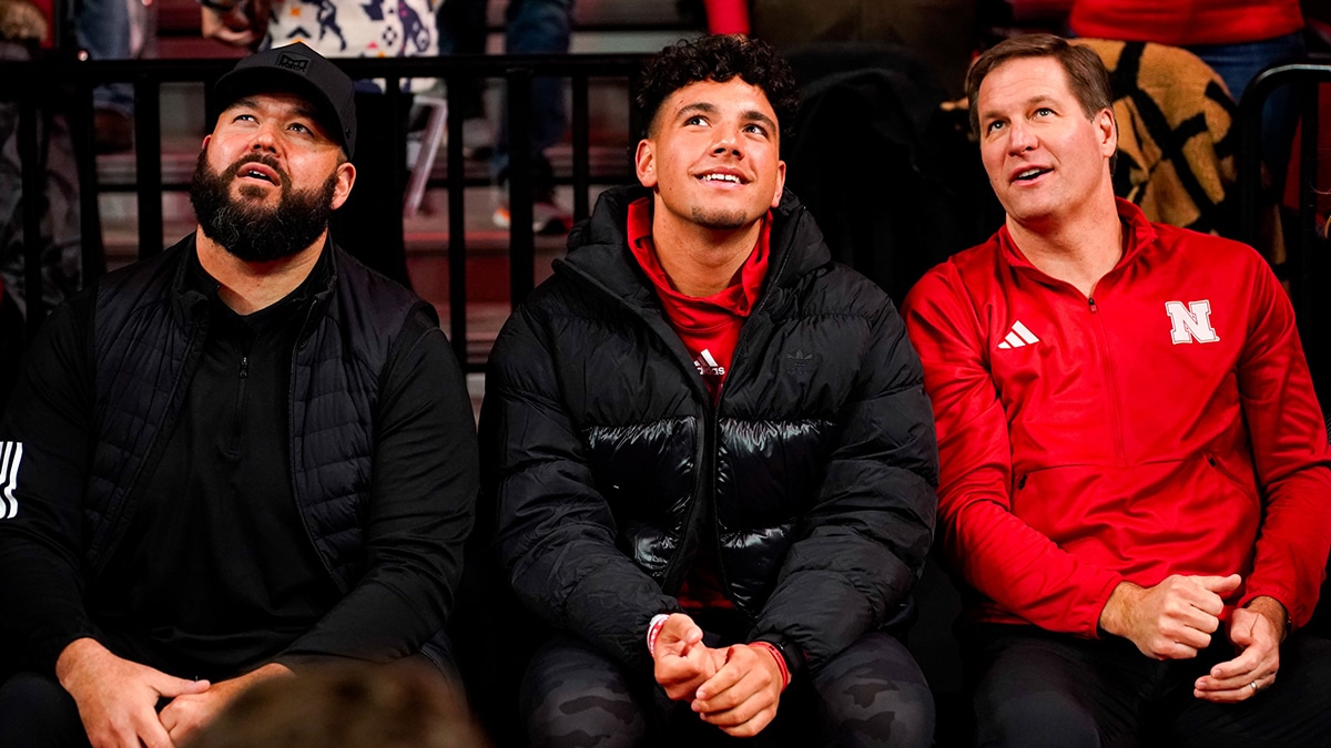 Jan 3, 2024; Lincoln, Nebraska, USA; Nebraska Cornhuskers football assistant coach Donovan Raiola (left), Dylan Raiola (center) and athletic director Trev Alberts sit courtside before the game against the Indiana Hoosiers at Pinnacle Bank Arena. Dylan is the top quarterback recruit in the 2024 class. Mandatory Credit: Dylan Widger-USA TODAY Sports