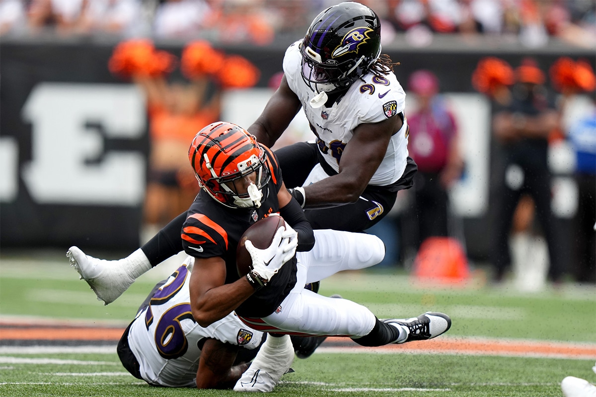 Cincinnati Bengals wide receiver Tyler Boyd (83) is tackled after a catch by Baltimore Ravens safety Geno Stone (26) and Baltimore Ravens linebacker David Ojabo (90) in the third quarter at Paycor Stadium. 