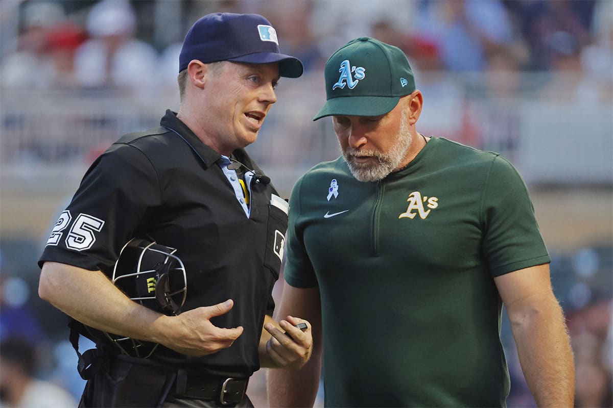 Home plate umpire Junior Valentine discusses with Oakland Athletics manager Mark Kotsay the ejection of pitching coach Scott Emerson in the fifth inning of game two of a double header with the Minnesota Twins at Target Field. 