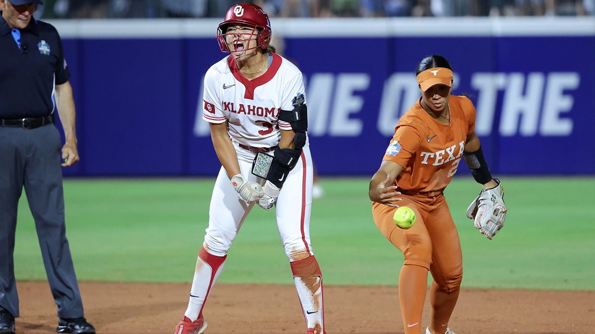 Oklahoma's Alyssa Brito (33) celebrates beside Texas infielder Viviana Martinez (23) after hitting a double in the seventh inning of the first game of the Women's College World Series softball championship series game between the Oklahoma Sooners (OU) and Texas Longhorns. Oklahoma won 8-3.