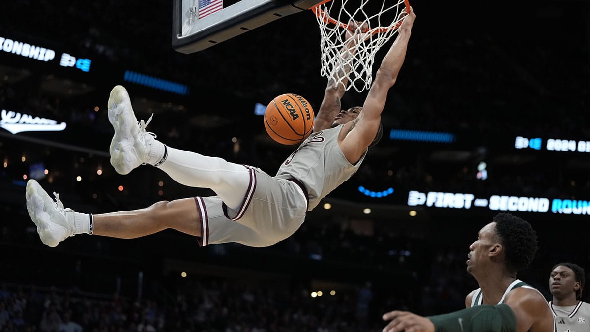Mississippi State Bulldogs guard Shakeel Moore (3) hangs onto the rim after a dunk against the Michigan State Spartans in the first round of the 2024 NCAA Tournament at the Spectrum Center. 