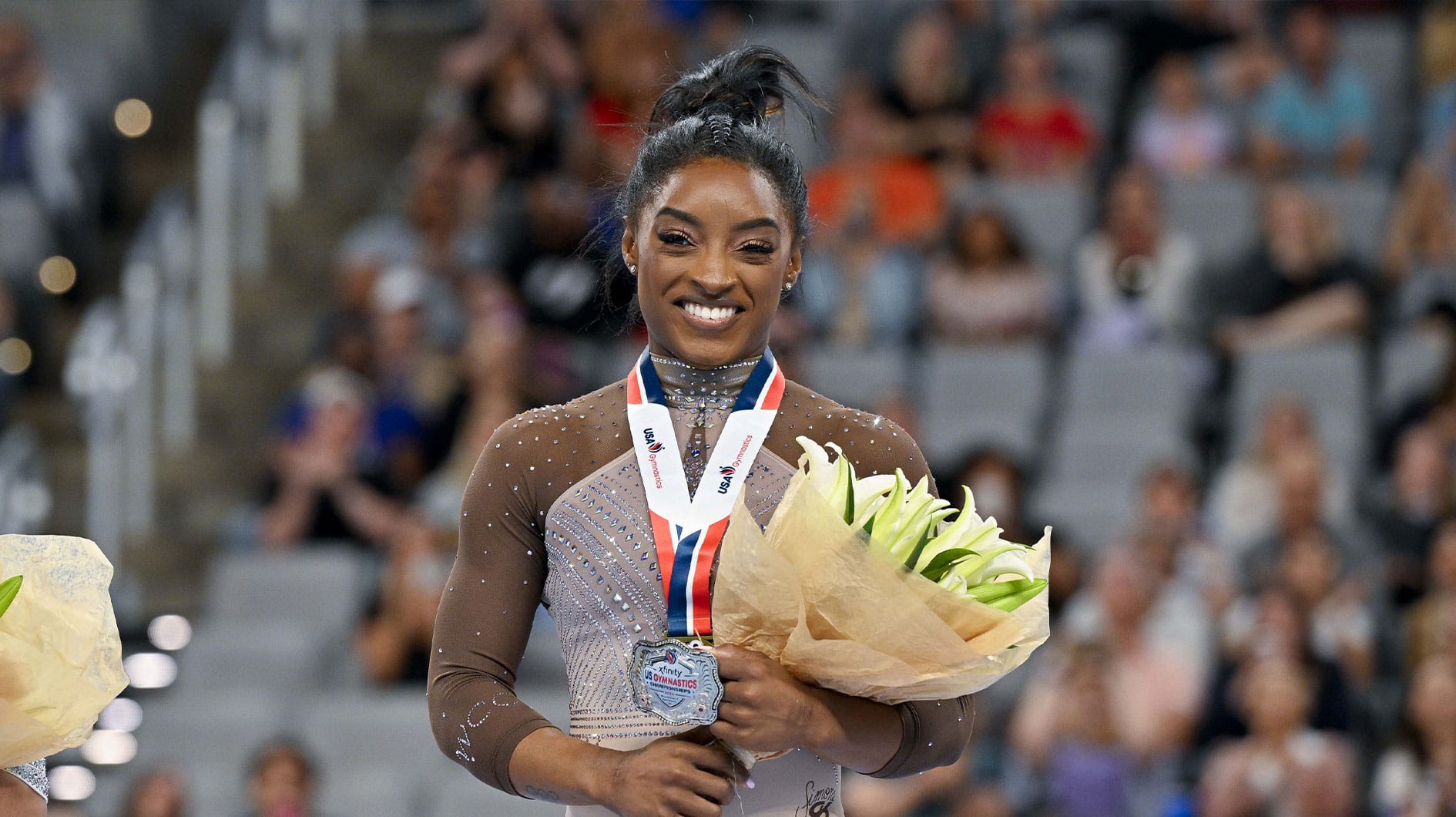 Simone Biles of World Champions Centre poses for a photo with her gold medal and commemorative belt buckle after finishing in first in the women’s 2024 Xfinity U.S. Gymnastics Championships at Dickies Arena.