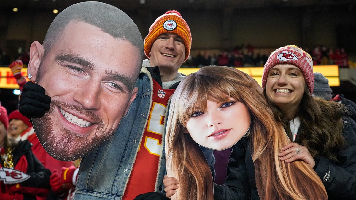 Chiefs fans wave Taylor Swift and Travis Kelce cutouts at Arrowhead Stadium.