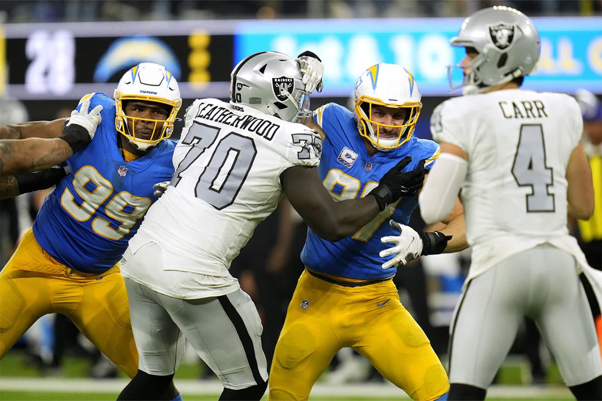 Los Angeles Chargers defensive tackle Jerry Tillery (99) and defensive end Joey Bosa (97) battle against Las Vegas Raiders offensive tackle Alex Leatherwood (70) as Raiders quarterback Derek Carr (4) drops back to pass during the second half at SoFi Stadium. 
