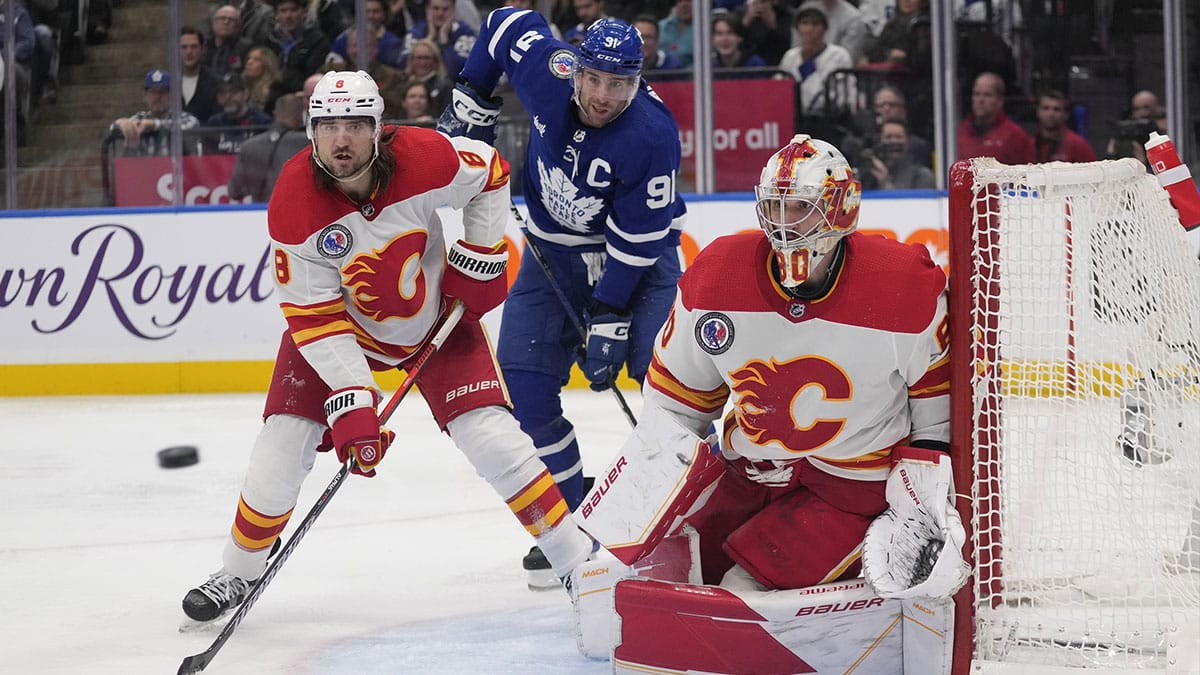 Calgary Flames goaltender Dan Vladar (80) goes to make a save as defenseman Chris Tanev (8) and Toronto Maple Leafs forward John Tavares (91) wait for a rebound during the third period at Scotiabank Arena