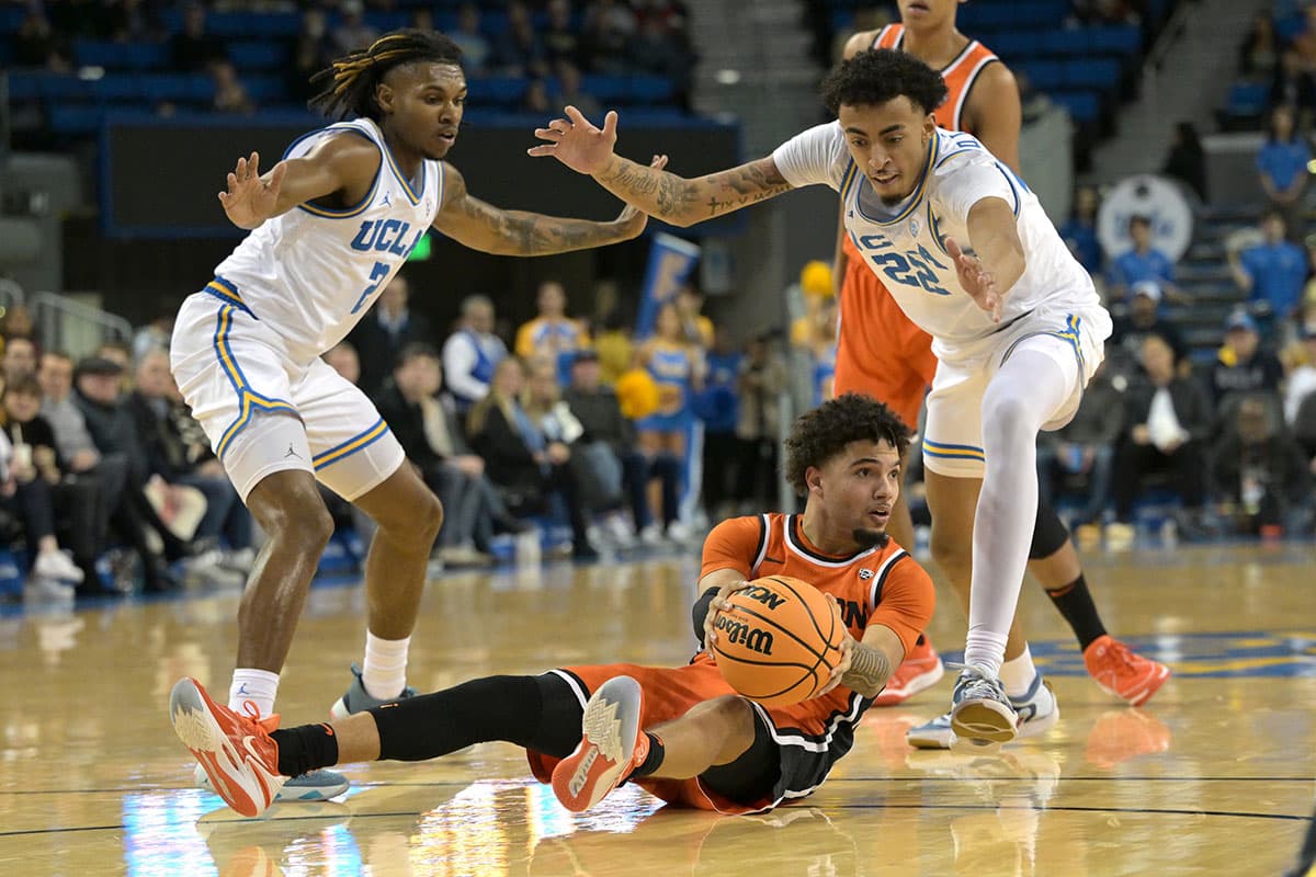 Oregon State Beavers guard Josiah Lake II (2) looks to pass after grabbing a loose ball as he is defended by UCLA Bruins forward Adem Bona (3) and forward Devin Williams (22) in the first half at Pauley Pavilion presented by Wescom.