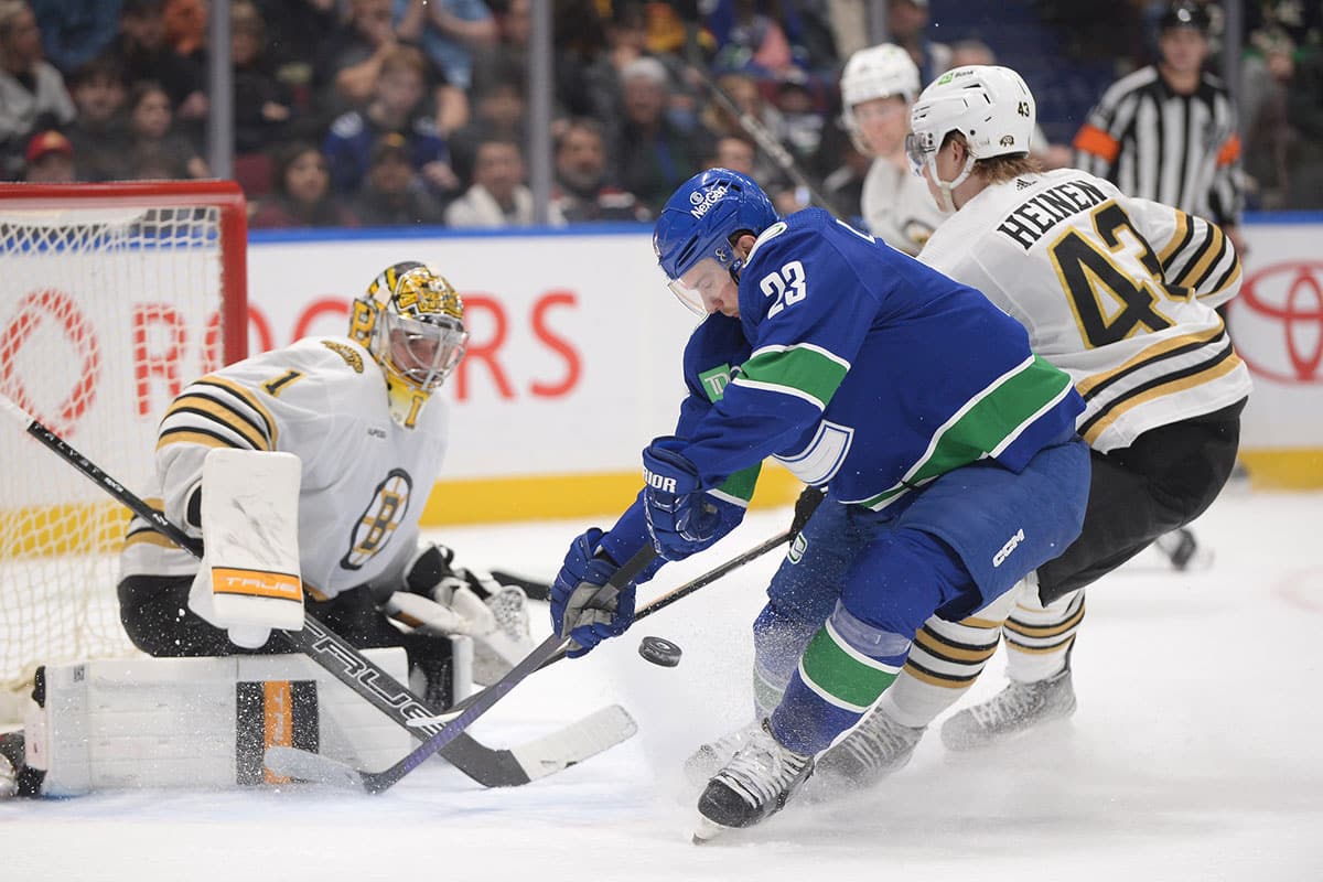 Boston Bruins goaltender Jeremy Swayman (1) and forward Danton Heinen (43) defend against Vancouver Canucks forward Elias Lindholm (23) during the third period at Rogers Arena.