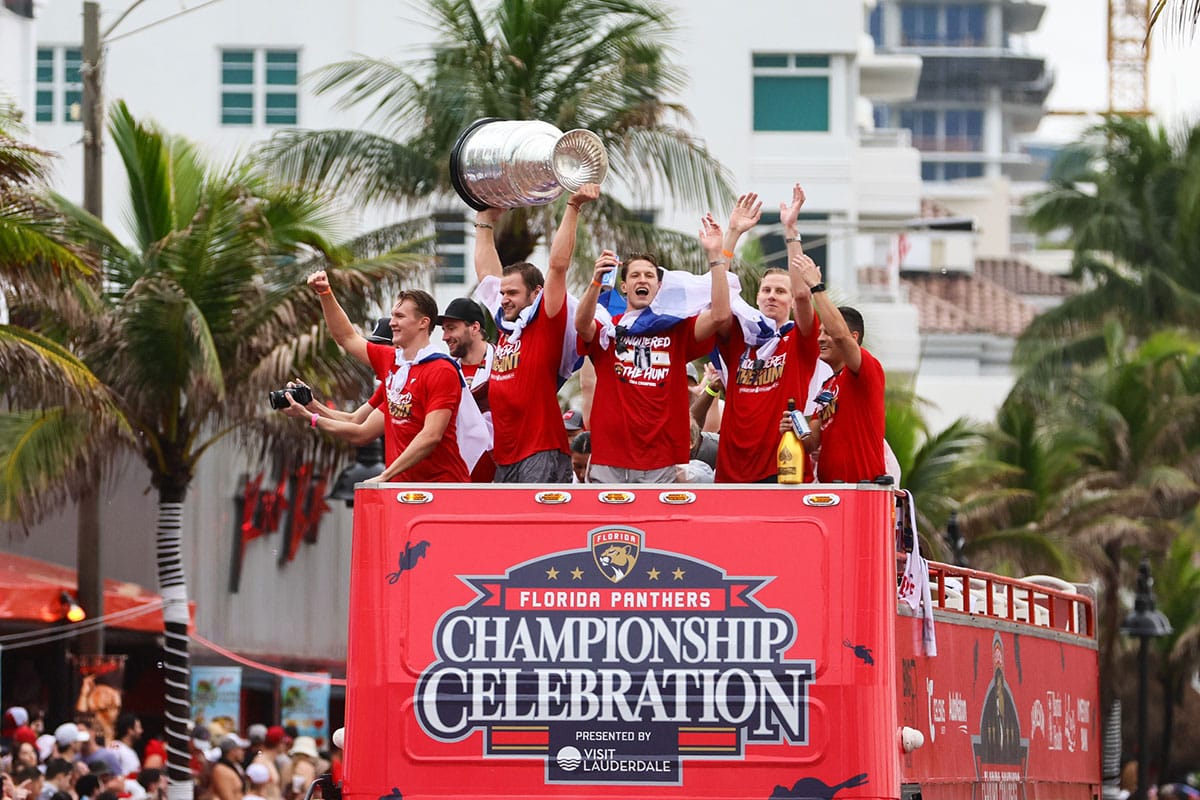 Florida Panthers center Aleksander Barkov hoists the cup while celebrating with Florida Panthers center Anton Lundell (left), center Eetu Luostarinen (center), and defenseman Niko Mikkola (77) during the Stanley Cup victory parade and celebration.