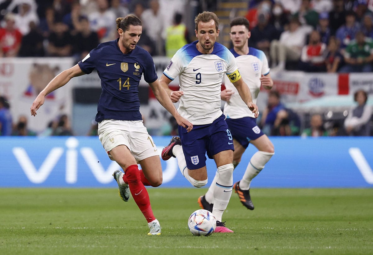 France midfielder Adrien Rabiot (14) dribbles in front of England forward Harry Kane (9) during the first half of a quarterfinal game in the 2022 FIFA World Cup at Al-Bayt Stadium