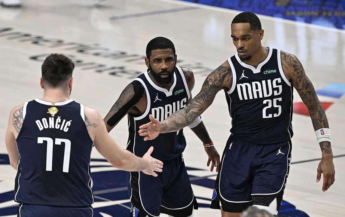 Dallas Mavericks guard Kyrie Irving (11) and forward P.J. Washington (25) celebrate with guard Luka Doncic (77) after a play during the fourth quarter in game three of the 2024 NBA Finals against the Boston Celtics at American Airlines Center.