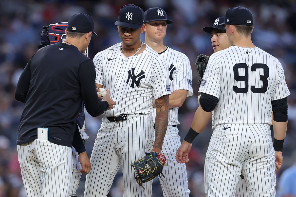 New York Yankees starting pitcher Luis Gil (81) hands the ball to manager Aaron Boone (17) after being taken out of the game against the Cincinnati Reds during the fifth inning at Yankee Stadium.
