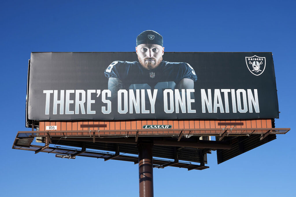 A billboard featuring image of Las Vegas Raiders defensive end Maxx Crosby (98) and words \"There's only one nation\" on E. Hidden Well Rd. 