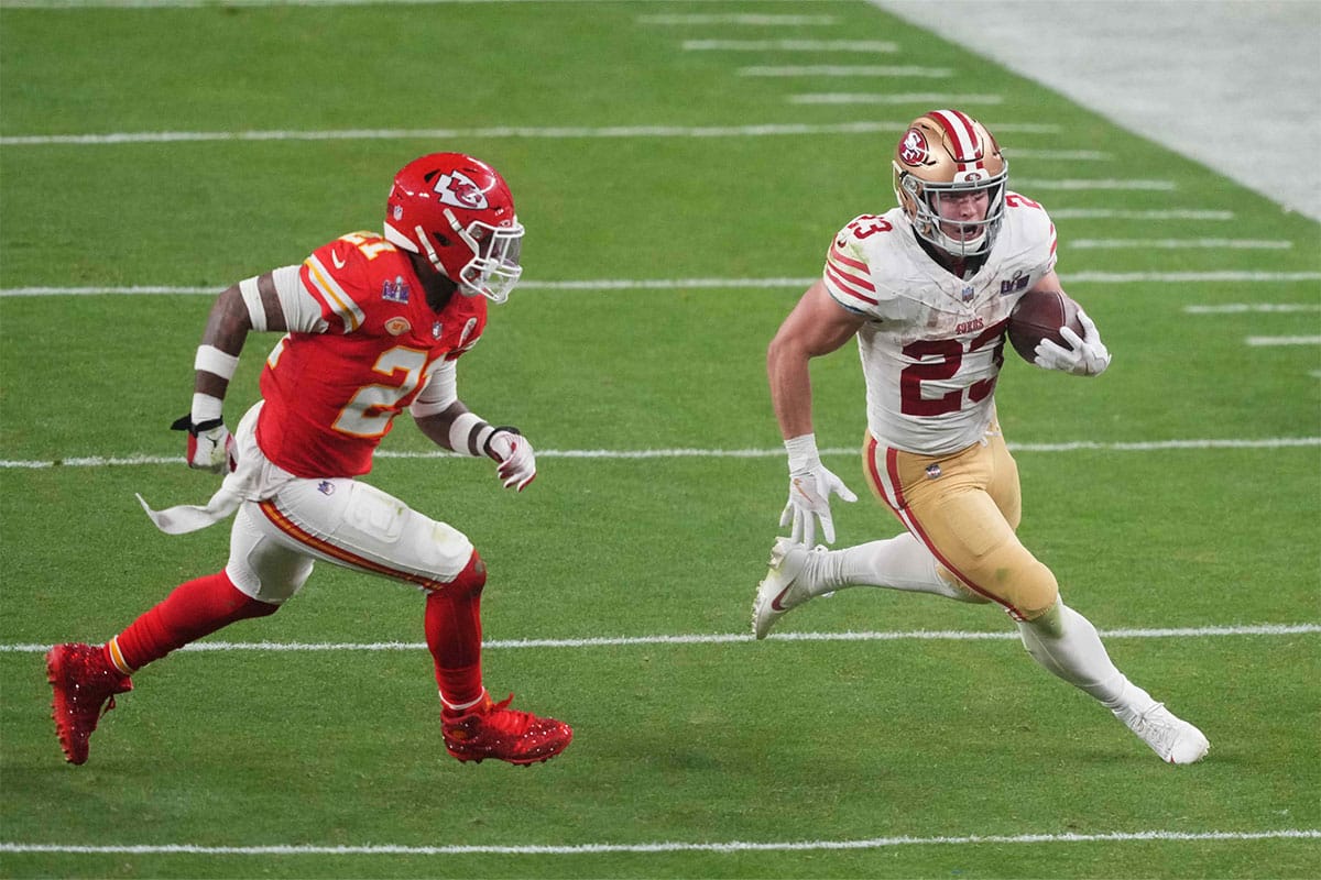 San Francisco 49ers running back Christian McCaffrey (23) runs with the ball against Kansas City Chiefs safety Mike Edwards (21) during overtime of Super Bowl LVIII at Allegiant Stadium.