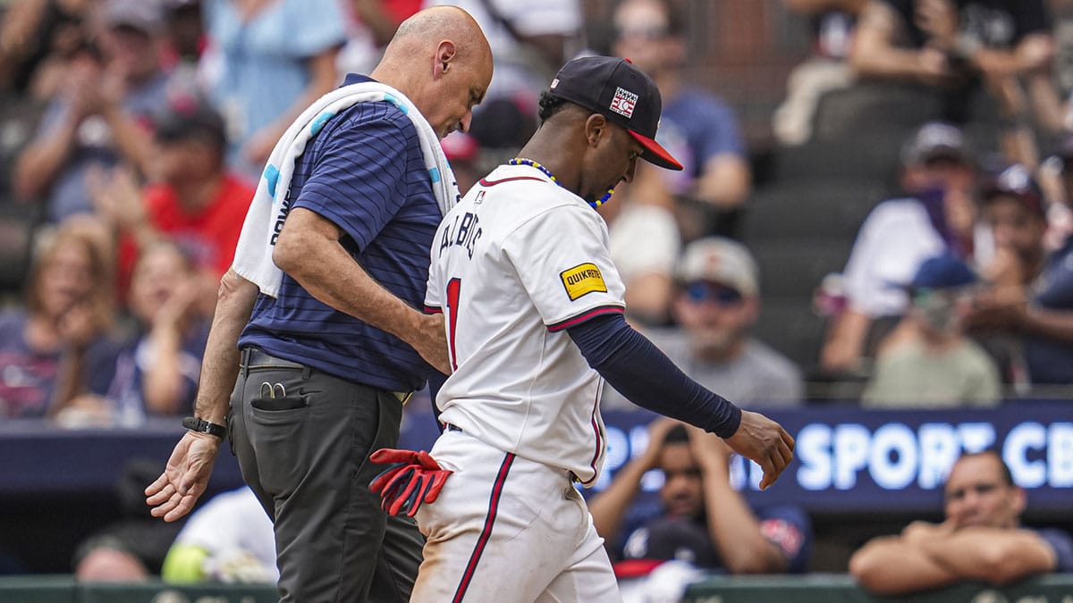 Atlanta Braves second baseman Ozzie Albies (1) is assisted off the field after being injured during a play against the St. Louis Cardinals during the ninth inning at Truist Park.