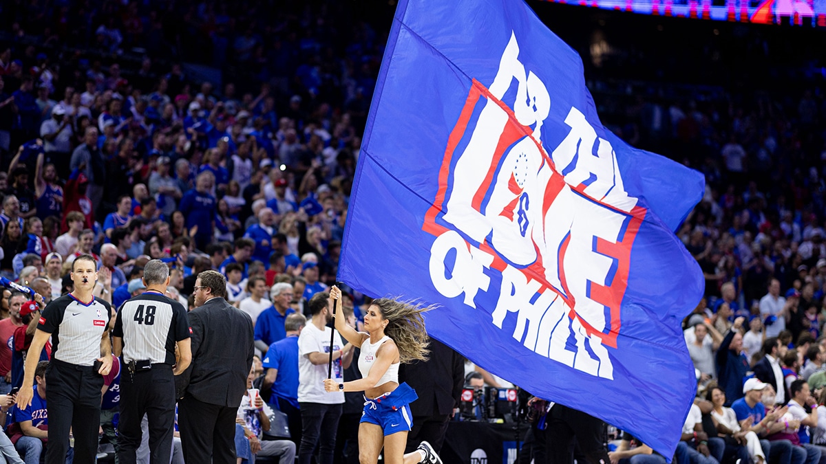Philadelphia 76ers entertainer runs with a large flag during the first half of game six of the first round for the 2024 NBA playoffs against the New York Knicks at Wells Fargo Center. 