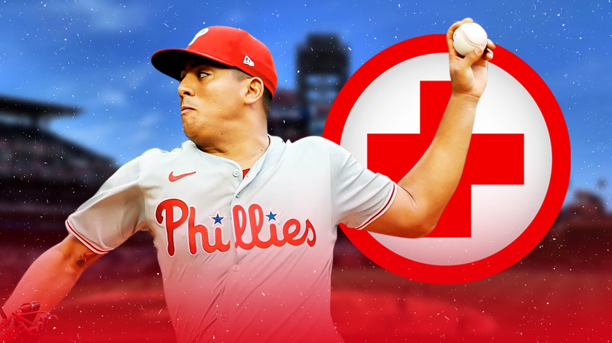 Ranger Suarez pitching in a Philadelphia Phillies uniform with a red first aid/medical symbol to indicate his injury (as the Phillies pitcher was moved the the injured list as latest Phillies injuries.