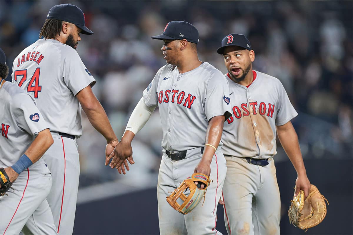 Boston Red Sox third baseman Rafael Devers (11) celebrates with relief pitcher Kenley Jansen (74) and first baseman Dominic Smith (2) after defeating the New York Yankees at Yankee Stadium.