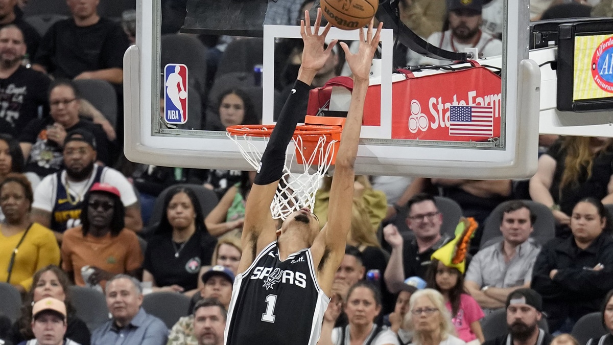 San Antonio Spurs forward Victor Wembanyama (1) reaches above the rim for a pass during the second half against the Denver Nuggets at Frost Bank Center