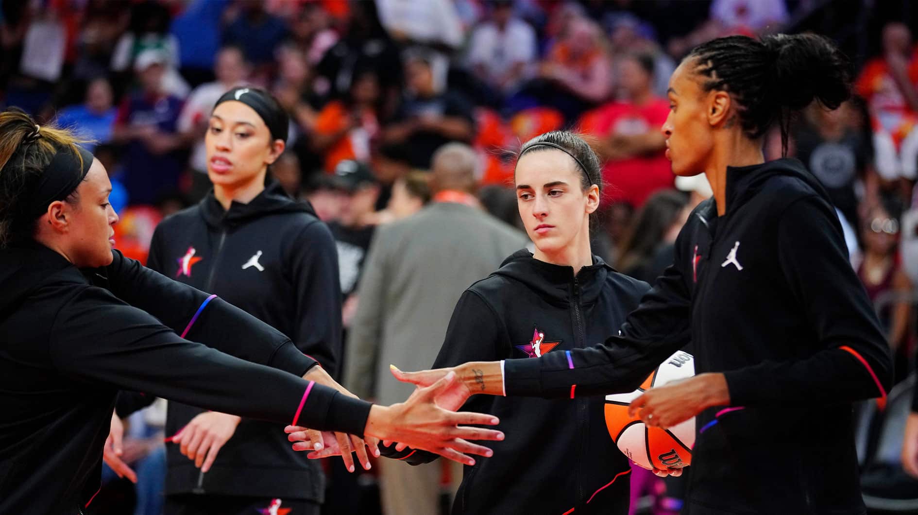 Team WNBA player Caitlin Clark high fives teammates Kayla McBride and DeWanna Bonner