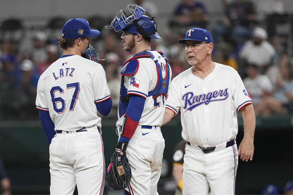 Texas Rangers relief pitcher Jacob Latz (67) is relieved of his duties by manager Bruce Bochy (15) as catcher Jonah Heim (28) looks on during the sixth inning against the San Diego Padres at Globe Life Field.
