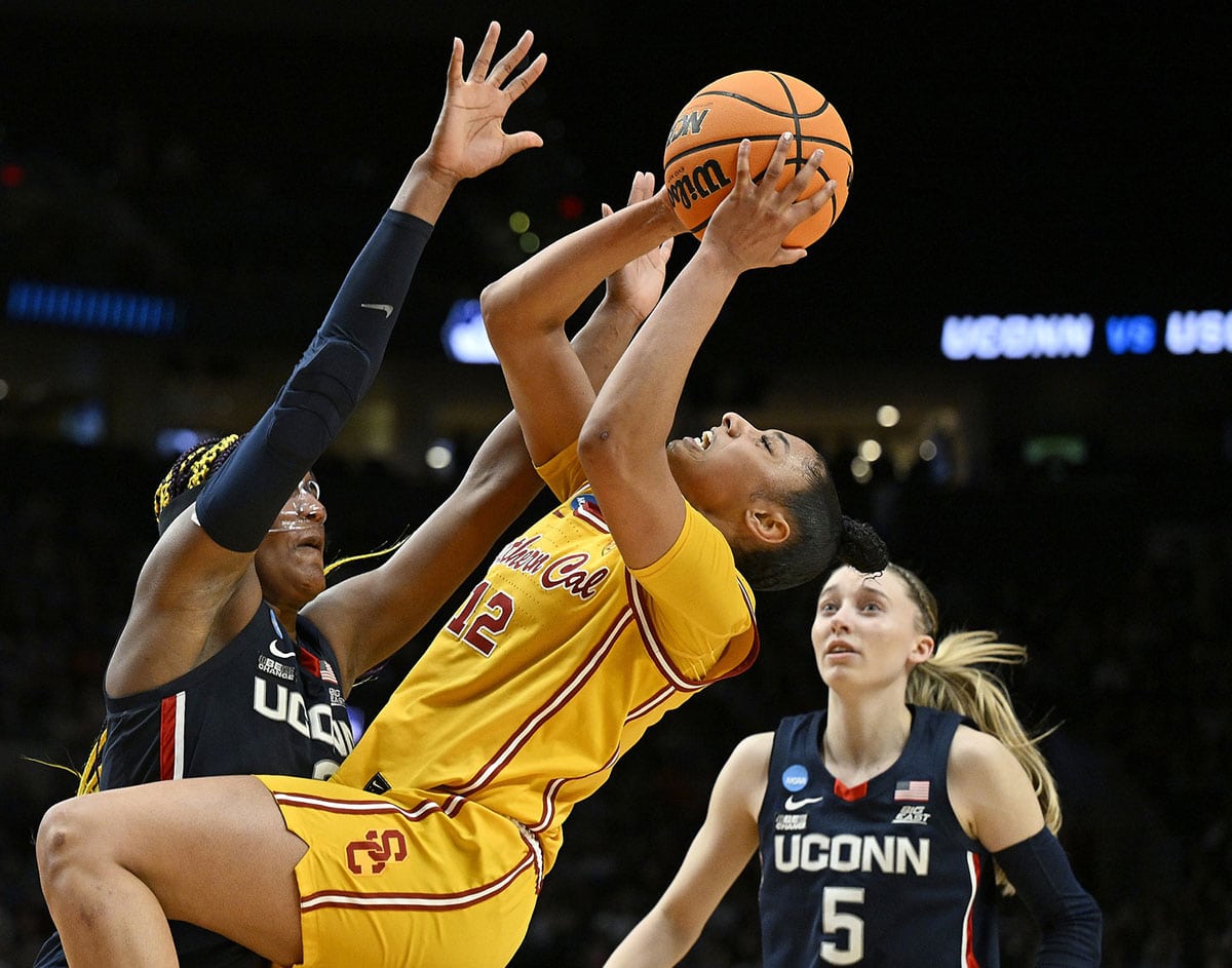 Apr 1, 2024; Portland, OR, USA; USC Trojans guard JuJu Watkins (12) puts up a shot during the second half against UConn Huskies forward Aaliyah Edwards (3) and guard Paige Bueckers (5) in the finals of the Portland Regional of the NCAA Tournament at the Moda Center. Mandatory Credit: Troy Wayrynen-USA TODAY Sports