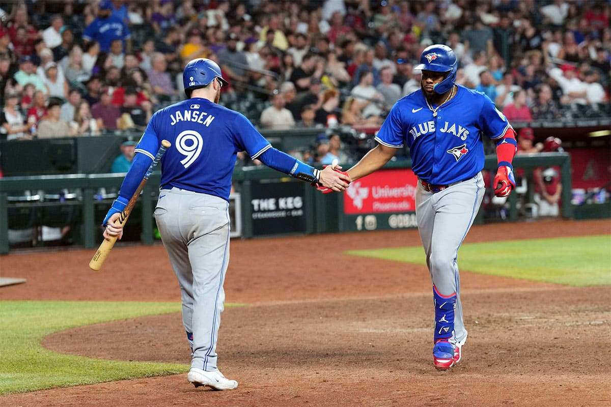 Toronto Blue Jays first base Vladimir Guerrero Jr. (27) slaps hands with Toronto Blue Jays catcher Danny Jansen (9) after hitting a solo home run against the Arizona Diamondbacks during the seventh inning at Chase Field.