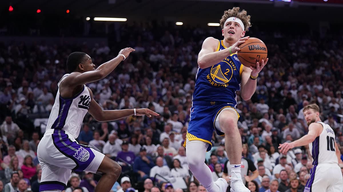 Golden State Warriors guard Brandin Podziemski (2) makes a layup next to Sacramento Kings guard De'Aaron Fox (5) in the second quarter during a play-in game of the 2024 NBA playoffs at the Golden 1 Center.