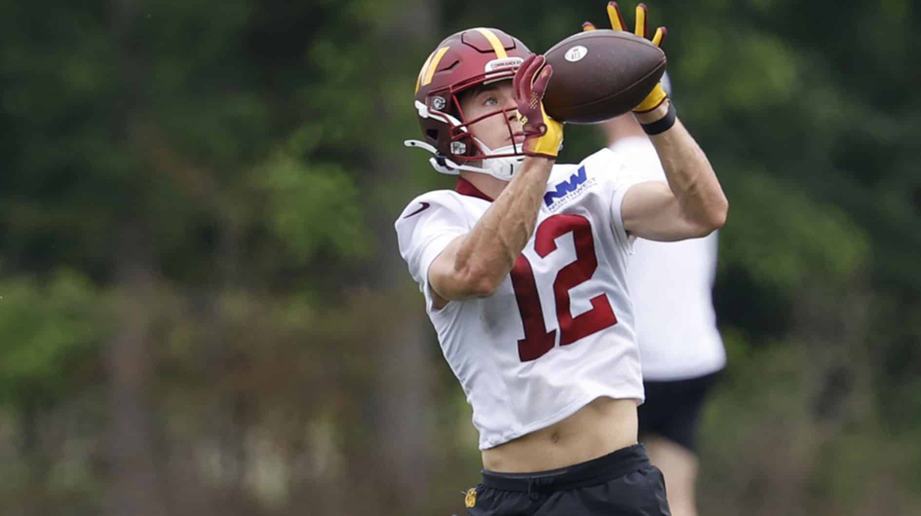 Washington Commanders wide receiver Luke McCaffrey (12) catches a pass during an OTA workout at Commanders Park.
