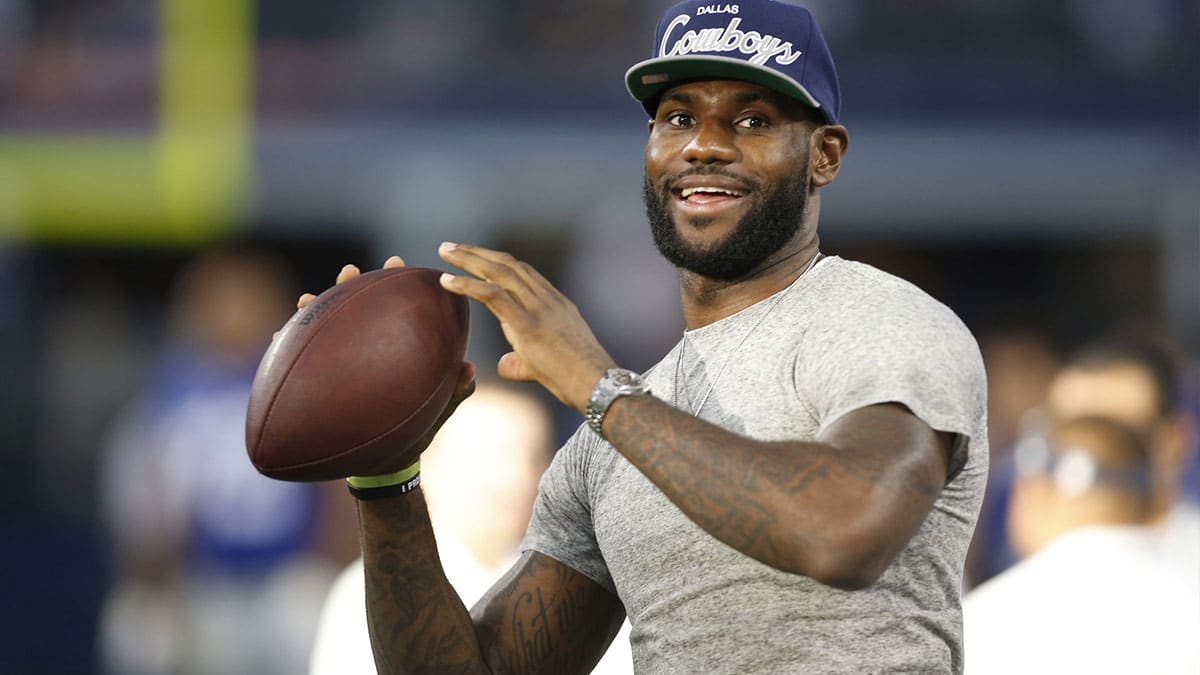 Miami Heat guard LeBron James throws a football on the sidelines of the game between the Dallas Cowboys and the New York Giants at AT&T Stadium. 