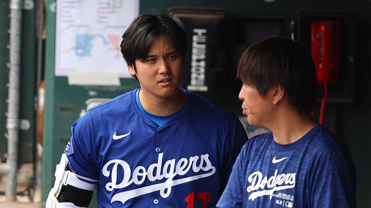 Los Angeles Dodgers designated hitter Shohei Ohtani talks with translator Ippei Mizuhara in the dugout against the San Francisco Giants during a spring training baseball game at Camelback Ranch-Glendale.