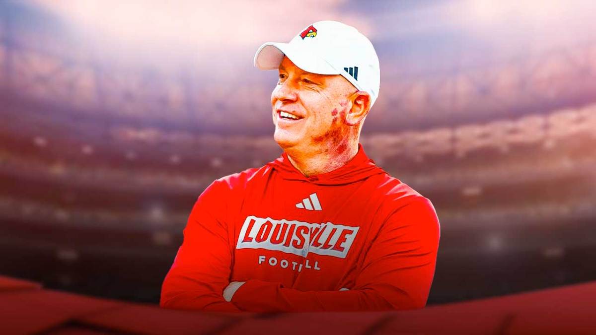 Jeff Brohm smiles in Louisville Cardinals gear