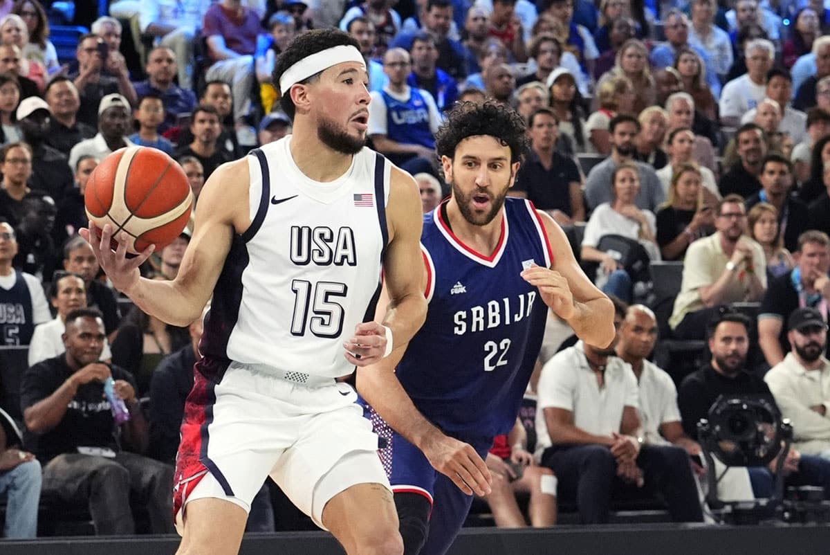 United States guard Devin Booker (15) controls the ball /while defended by Serbia point guard Vasilije Micic (22) during the first half in a men's basketball semifinal game during the Paris 2024 Olympic Summer Games at Accor Arena.