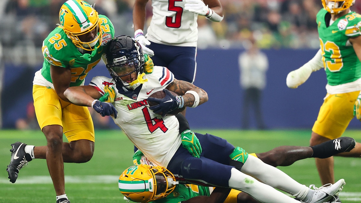 Liberty Flames wide receiver CJ Daniels (4) is tackled by Oregon Ducks defensive back Nikko Reed (25) and linebacker Jeffrey Bassa (2) during the first quarter of the 2024 Fiesta Bowl at State Farm Stadium. 