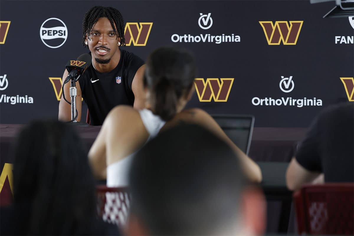 Washington Commanders quarterback Jayden Daniels (L) speaks with the media after morning practice on day three of training camp at Commanders Park.