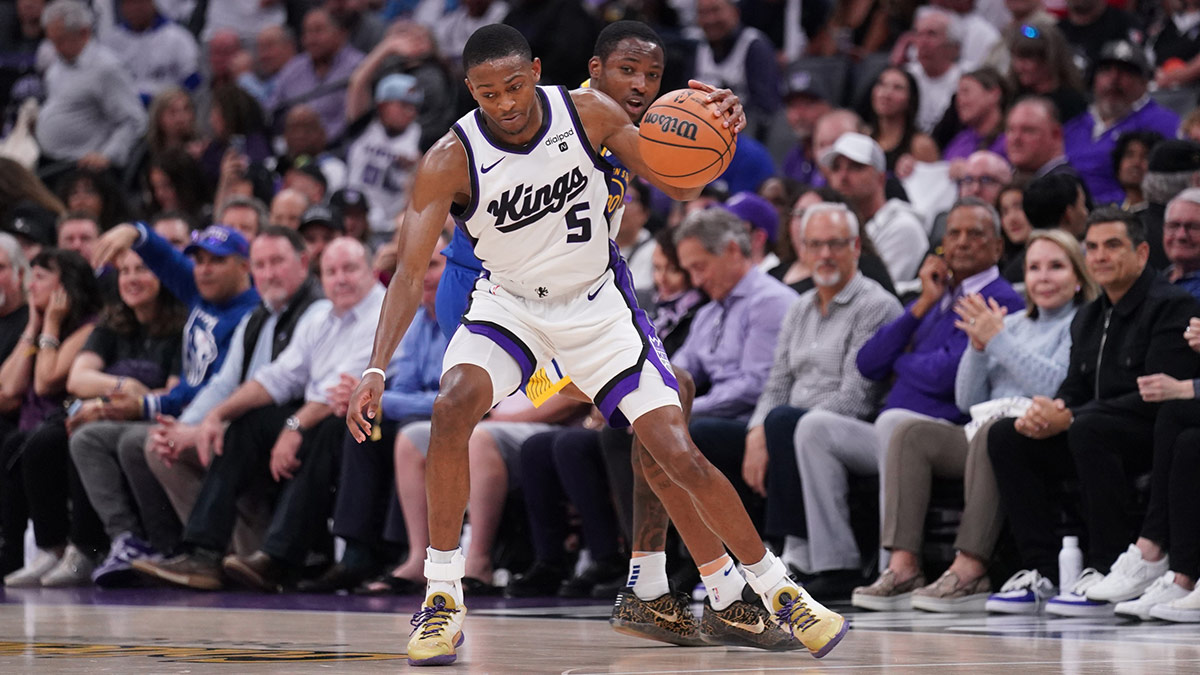 Sacramento Kings guard De'Aaron Fox (5) dribbles the ball in front of Golden State Warriors forward Jonathan Kuminga (00) in the fourth quarter during a play-in game of the 2024 NBA playoffs at the Golden 1 Center.