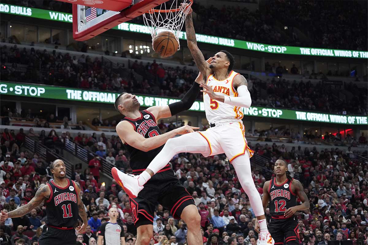 Atlanta Hawks guard Dejounte Murray (5) dunks the ball on Chicago Bulls center Nikola Vucevic (9) during the second half during a play-in game of the 2024 NBA playoffs at United Center.