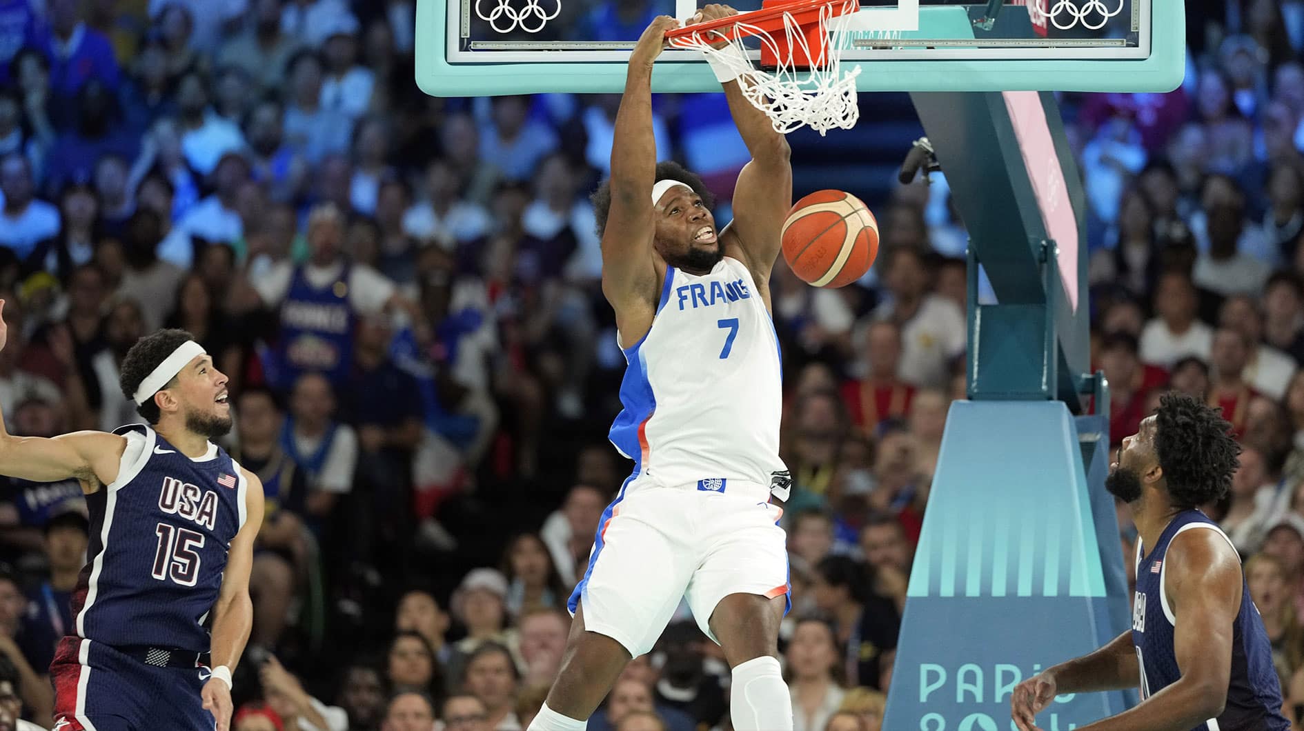 France power forward Guerschon Yabusele (7) dunks against United States guard Devin Booker (15) and centre Joel Embiid (11) in the first quarter in the men's basketball gold medal game during the Paris 2024 Olympic Summer Games at Accor Arena.