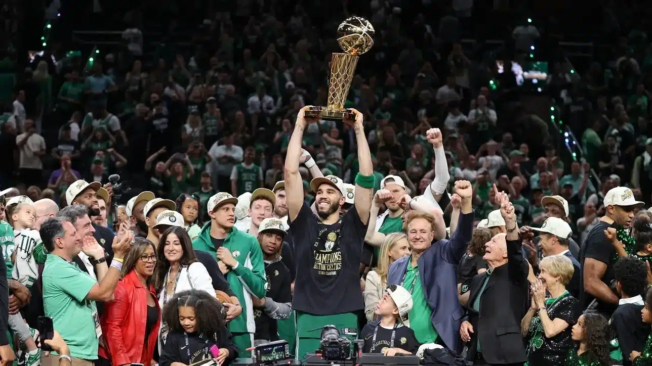 Boston Celtics forward Jayson Tatum (0) lifts the trophy after winning the 2024 NBA Finals against the Dallas Mavericks at TD Garden.