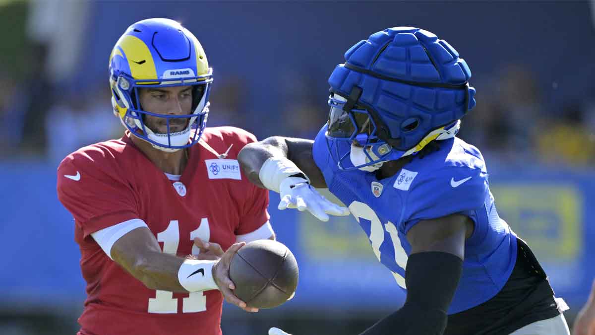 Los Angeles Rams quarterback Jimmy Garoppolo (11) hands off to running back Zach Evans (21) during training camp at Loyola Marymount University.