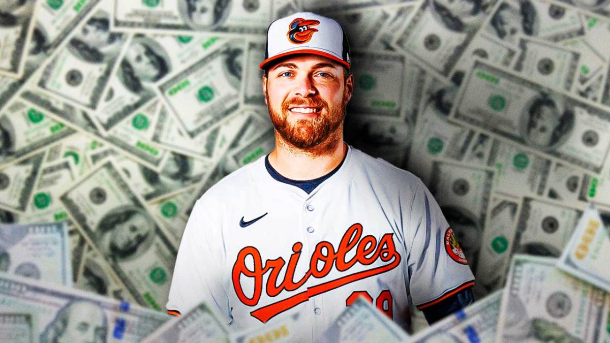 Orioles' Corbin Burnes smiling, lying on a bed filled with cash